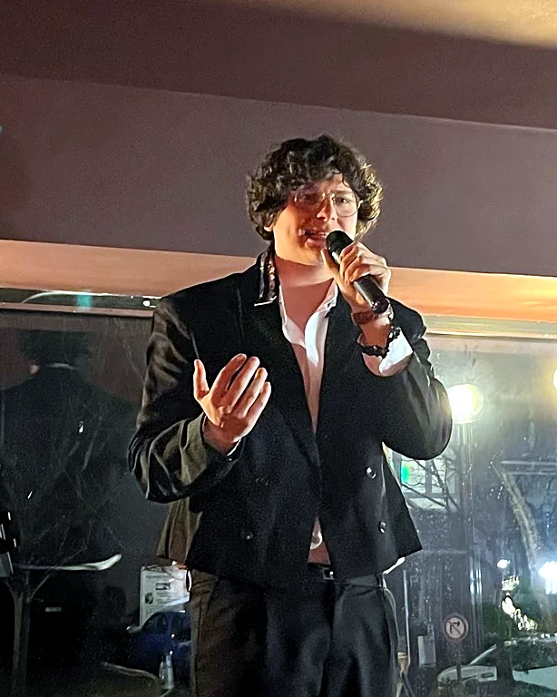 François Thiry chante en live dans un bar, de nuit, devant la vitrine