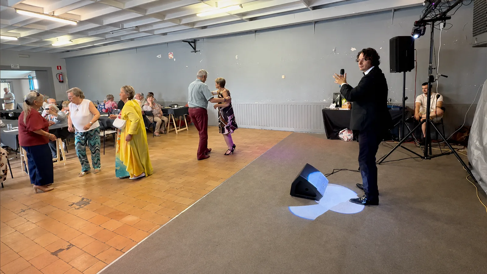François Thiry chante au micro pendant qu'un couple danse sur la piste d'un thé dansant